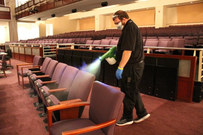 DECPA staff member cleans seats between performances with an alcohol mist