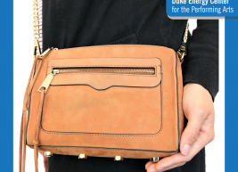 an image of a person wearing a black shirt with a tan crossbody bag over the shoulder their left hand is to the side of the bag